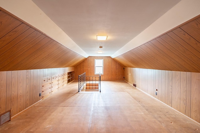 additional living space featuring vaulted ceiling, wood walls, and visible vents