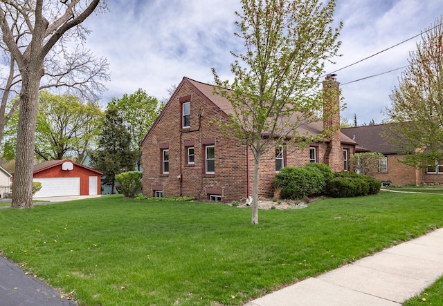 view of side of property featuring brick siding, a garage, an outbuilding, a chimney, and a lawn