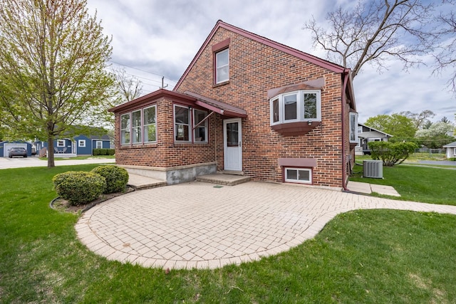 back of property featuring brick siding, a patio area, a yard, and cooling unit