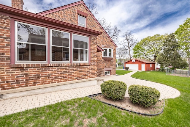 view of home's exterior with brick siding, an outdoor structure, a yard, and a detached garage