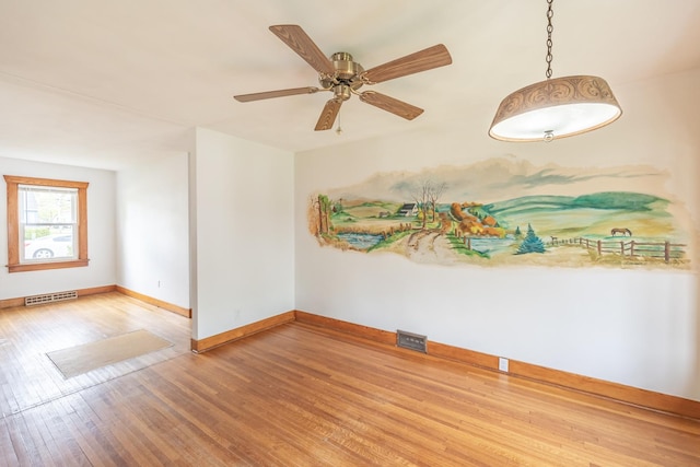 empty room featuring baseboards, a ceiling fan, wood finished floors, and visible vents