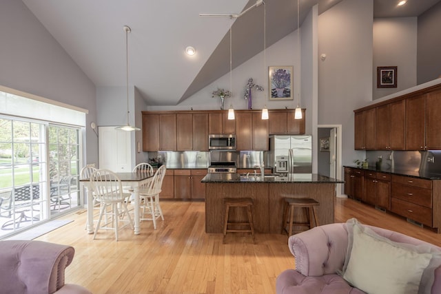 825 Canton Dr, Oswego, IL 60543 - kitchen with light wood-style floors, a kitchen breakfast bar, a center island with sink, high vaulted ceiling, and stainless steel appliances