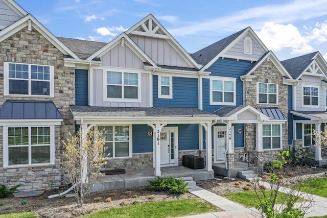 townhome / multi-family property featuring covered porch, board and batten siding, a shingled roof, and stone siding