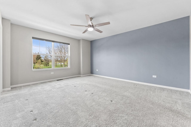carpeted spare room with a ceiling fan and baseboards