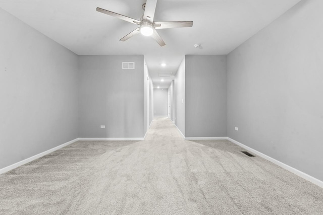 carpeted spare room featuring visible vents, a ceiling fan, baseboards, and attic access