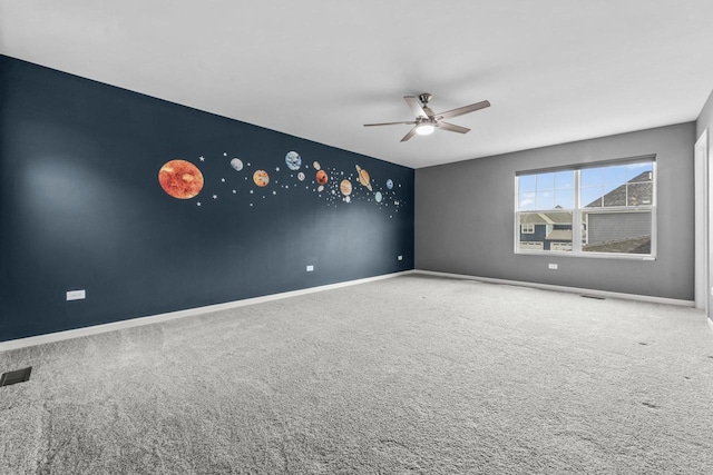spare room with a ceiling fan, baseboards, visible vents, and carpet