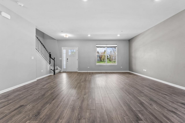 unfurnished living room with recessed lighting, baseboards, dark wood finished floors, and stairs