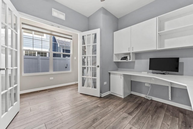 unfurnished office featuring built in study area, french doors, dark wood-style floors, and visible vents