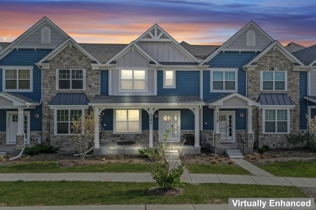 townhome / multi-family property with roof with shingles, board and batten siding, a porch, and stone siding