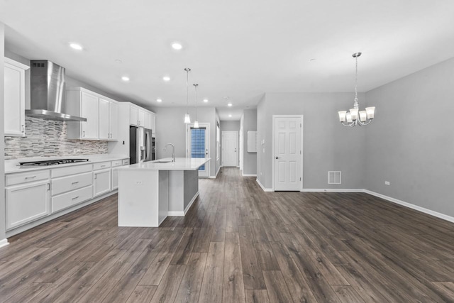 kitchen featuring a notable chandelier, a sink, stainless steel fridge with ice dispenser, wall chimney exhaust hood, and gas stovetop