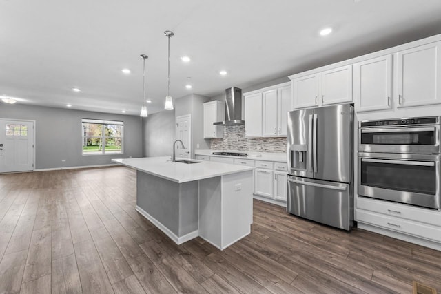 kitchen with dark wood-type flooring, a sink, wall chimney exhaust hood, and stainless steel appliances