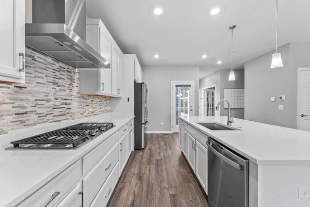 kitchen featuring wall chimney range hood, appliances with stainless steel finishes, a sink, light countertops, and recessed lighting
