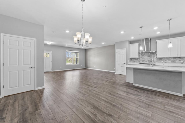 unfurnished living room featuring a notable chandelier, a sink, dark wood finished floors, recessed lighting, and baseboards