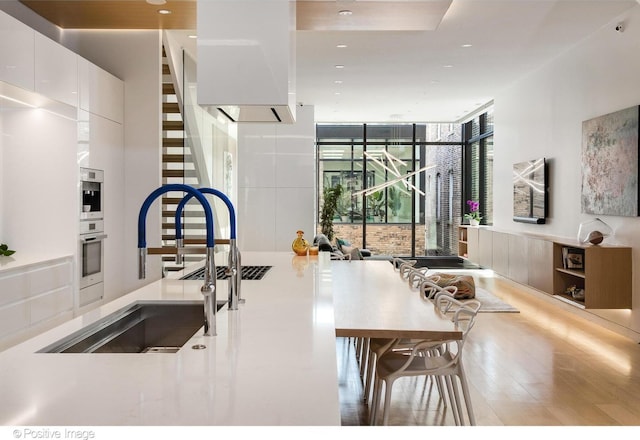 1833 W Evergreen Ave, Chicago, IL 60622 - kitchen with wood finished floors, expansive windows, a sink, recessed lighting, and white cabinetry