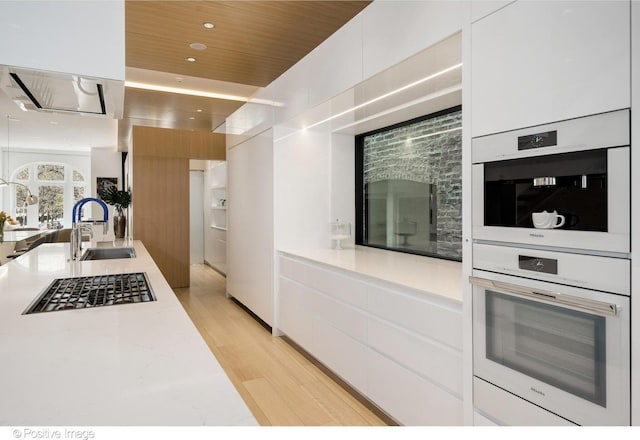 1833 W Evergreen Ave, Chicago, IL 60622 - kitchen with modern cabinets, light countertops, white cabinets, a sink, and light wood finished floors