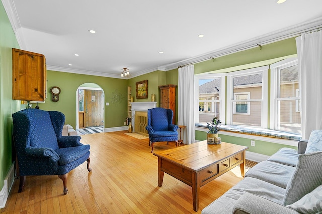 living area with baseboards, light wood-type flooring, arched walkways, and a healthy amount of sunlight