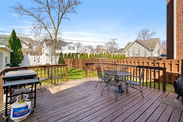 deck with area for grilling, a fenced backyard, a residential view, and outdoor dining area