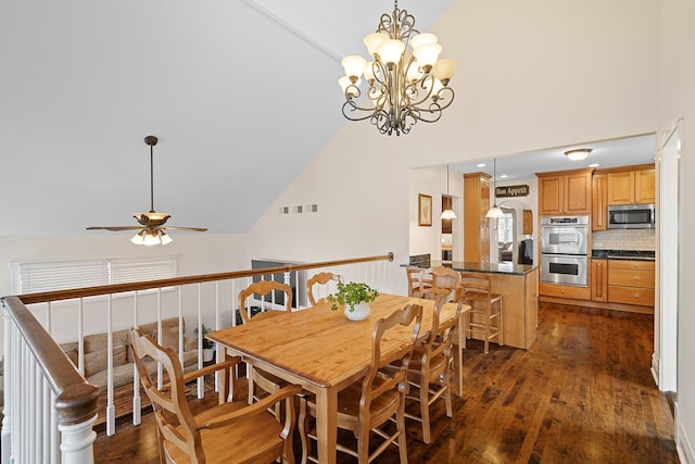 dining space featuring dark wood-type flooring, high vaulted ceiling, and ceiling fan with notable chandelier