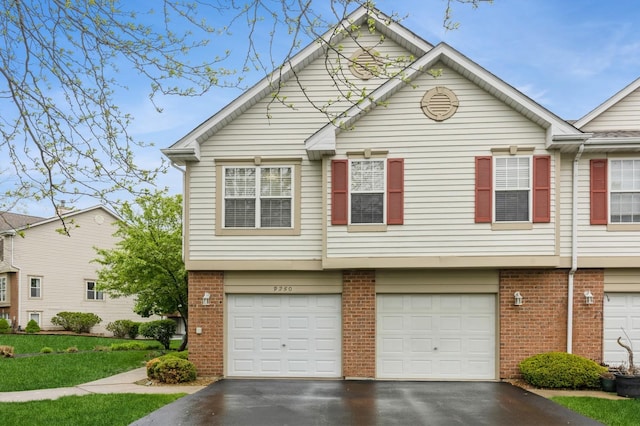 view of property with brick siding, a garage, and driveway