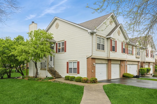 view of home's exterior featuring brick siding, a garage, aphalt driveway, a chimney, and a yard