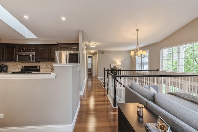 hallway featuring a skylight, wood finished floors, an upstairs landing, an inviting chandelier, and recessed lighting