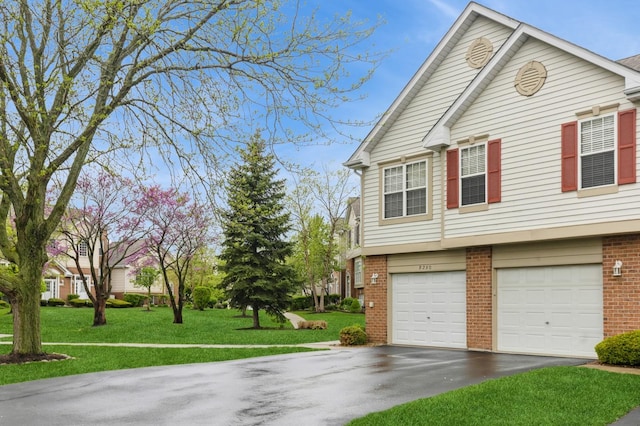 view of front of property with brick siding, a garage, driveway, and a front yard