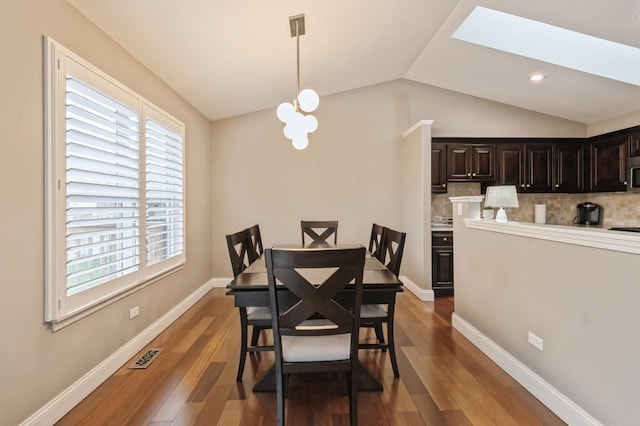 dining space featuring visible vents, dark wood-style flooring, lofted ceiling with skylight, and a healthy amount of sunlight