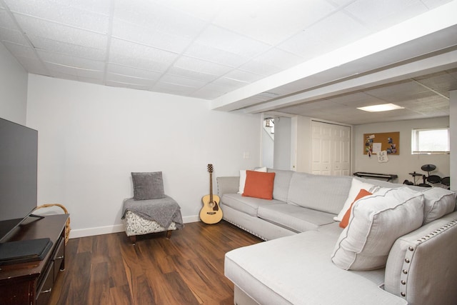 living area with baseboards, a drop ceiling, and wood finished floors