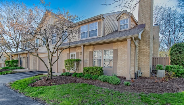 3094 Anton Cir Unit 3094, Aurora, IL 60504 - view of front of house featuring aphalt driveway, a chimney, an attached garage, fence, and central AC unit