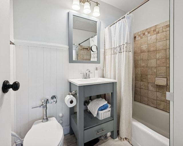 bathroom featuring a wainscoted wall, shower / bath combination with curtain, and a sink
