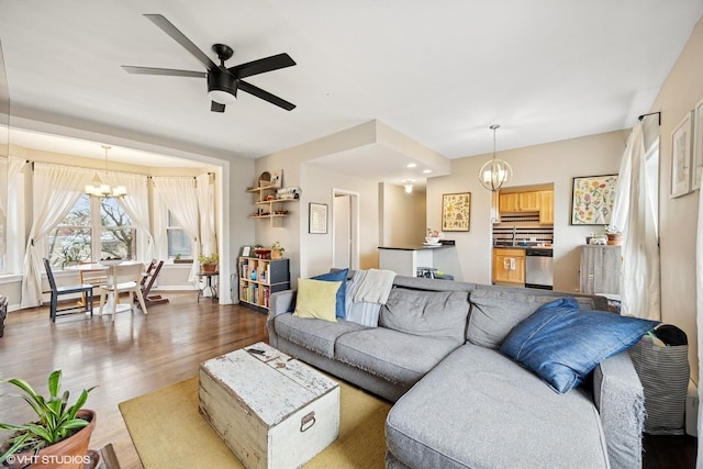 living room with baseboards, dark wood finished floors, and ceiling fan with notable chandelier