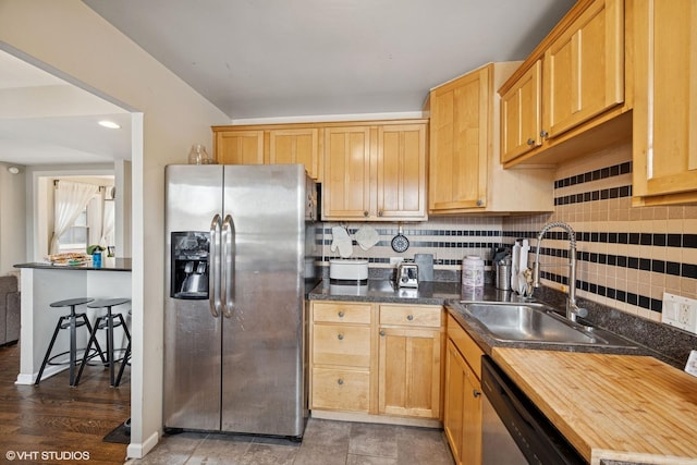 kitchen featuring a sink, appliances with stainless steel finishes, light brown cabinetry, and backsplash