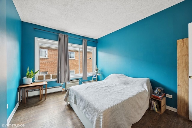 bedroom with baseboards, a baseboard radiator, wood finished floors, and baseboard heating
