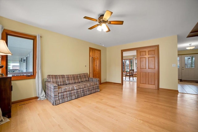 living area with baseboards, ceiling fan, wood finished floors, and visible vents