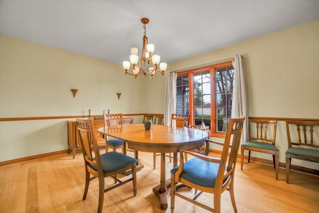 dining space with baseboards, light wood-style flooring, and a chandelier
