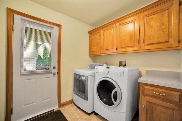 clothes washing area with baseboards, cabinet space, and washing machine and dryer