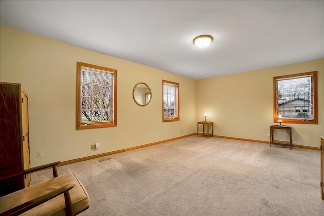 unfurnished room featuring a healthy amount of sunlight, baseboards, and light colored carpet