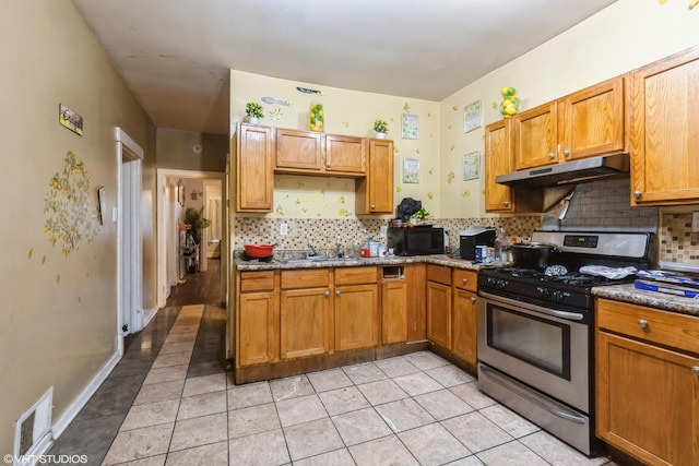 kitchen with black microwave, a sink, stainless steel gas range oven, under cabinet range hood, and visible vents