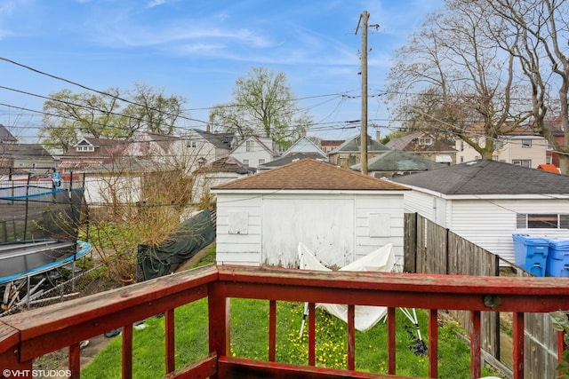 wooden terrace with a trampoline, a storage shed, a residential view, an outbuilding, and fence
