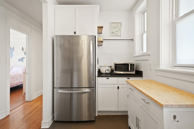 kitchen with wooden counters, backsplash, white cabinets, and appliances with stainless steel finishes
