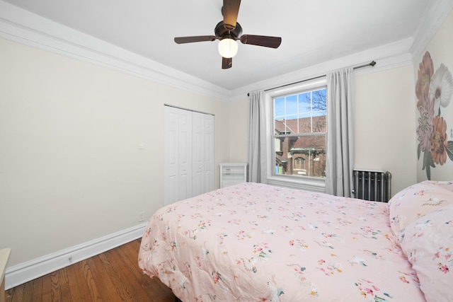 bedroom featuring ceiling fan, baseboards, a closet, radiator heating unit, and wood finished floors