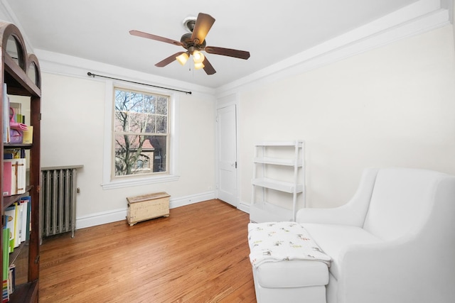 unfurnished room with a ceiling fan, light wood finished floors, baseboards, and radiator