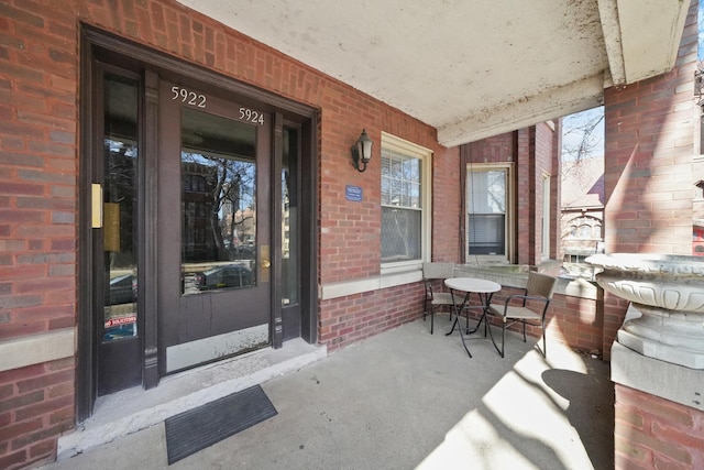 property entrance featuring a porch and brick siding