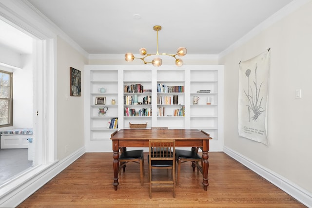 dining area with ornamental molding, an inviting chandelier, wood finished floors, and baseboards