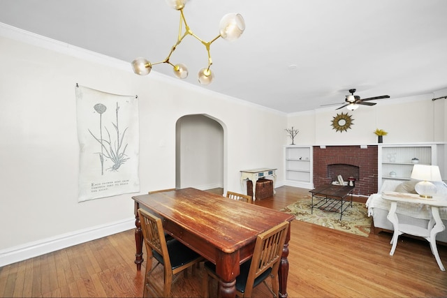 dining area with ceiling fan, baseboards, arched walkways, ornamental molding, and wood finished floors