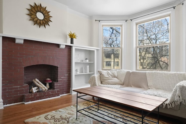living area featuring a brick fireplace, built in features, and wood finished floors