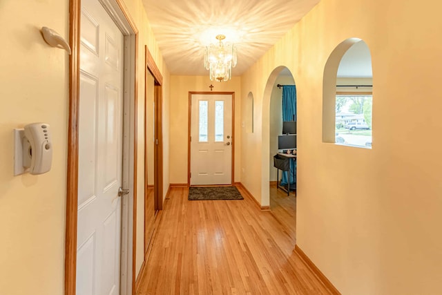 750 Evergreen Ln, Bartlett, IL 60103 - doorway to outside featuring arched walkways, light wood-style floors, baseboards, and a chandelier