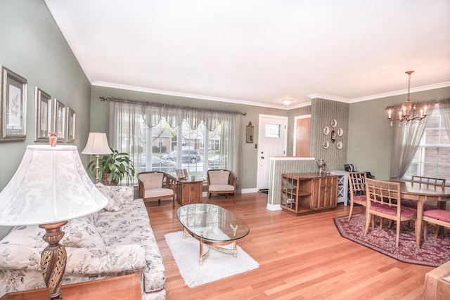 living room featuring crown molding, baseboards, wood finished floors, and a notable chandelier