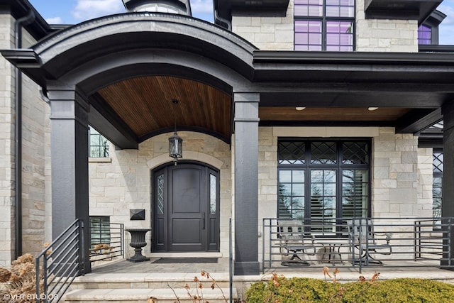 property entrance featuring covered porch and stone siding