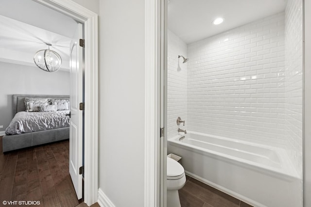 full bath with wood finished floors, bathtub / shower combination, a chandelier, toilet, and ensuite bathroom